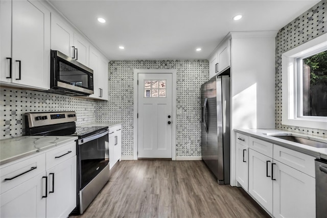 kitchen with dark hardwood / wood-style floors, decorative backsplash, light stone counters, white cabinetry, and stainless steel appliances