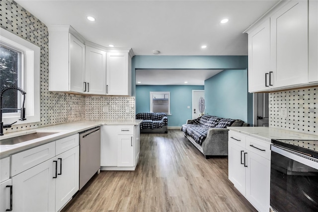 kitchen featuring light wood-type flooring, tasteful backsplash, stainless steel appliances, sink, and white cabinetry