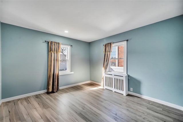 spare room with plenty of natural light, light wood-type flooring, and radiator