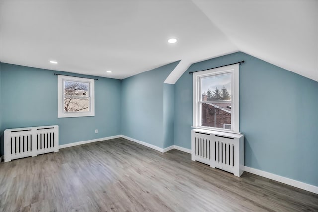 additional living space featuring radiator, light hardwood / wood-style flooring, and lofted ceiling