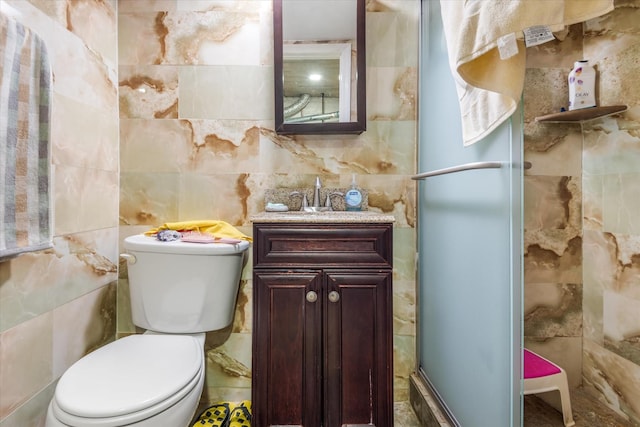 bathroom featuring an enclosed shower, vanity, toilet, and tile walls