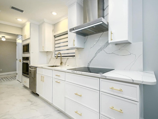 kitchen featuring decorative backsplash, appliances with stainless steel finishes, wall chimney exhaust hood, sink, and white cabinetry