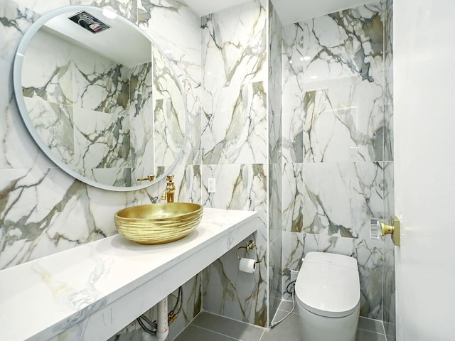 bathroom with toilet, sink, and tile walls