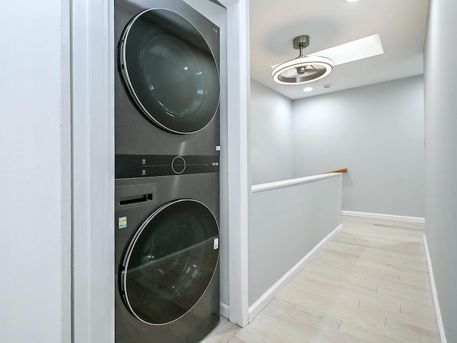 clothes washing area with stacked washing maching and dryer and light hardwood / wood-style floors