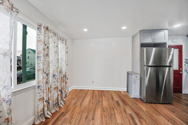 kitchen with stainless steel refrigerator, gray cabinetry, and light hardwood / wood-style floors