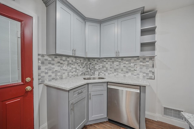 kitchen with backsplash, stainless steel dishwasher, sink, wood-type flooring, and gray cabinets