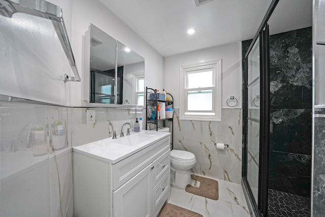 bathroom with tile walls, vanity, an enclosed shower, and toilet