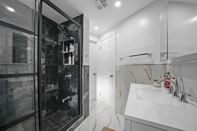 bathroom featuring vanity, an enclosed shower, and tile walls