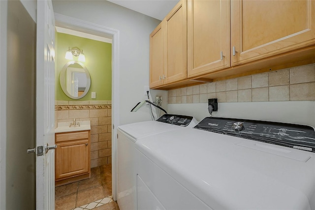 washroom with washing machine and clothes dryer, sink, cabinets, light tile patterned floors, and tile walls