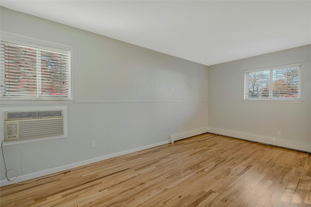 empty room featuring an AC wall unit and light hardwood / wood-style floors