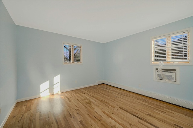 spare room featuring light hardwood / wood-style floors, a wall unit AC, and baseboard heating