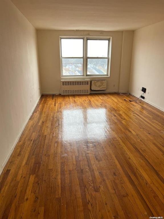 spare room with hardwood / wood-style floors and radiator heating unit