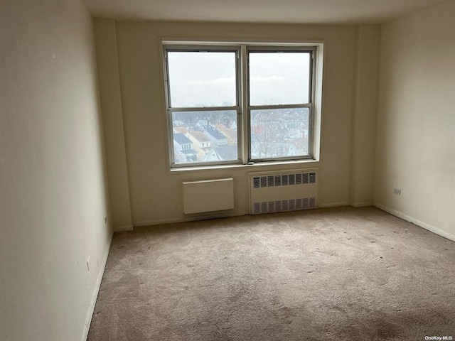 unfurnished room featuring radiator heating unit and light carpet