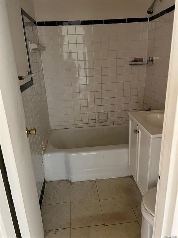 full bathroom featuring tile patterned flooring, vanity, tiled shower / bath combo, and toilet