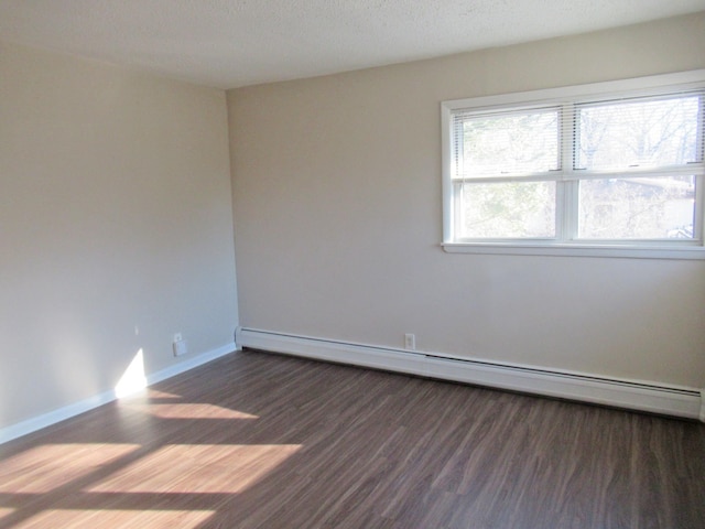 spare room featuring dark hardwood / wood-style flooring, a textured ceiling, and a baseboard heating unit