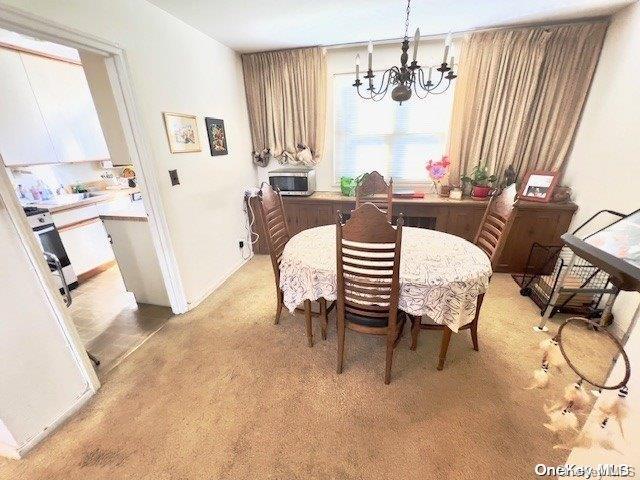 dining room with a chandelier and light colored carpet