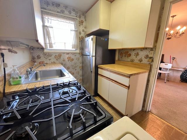 kitchen with carpet, wooden counters, white cabinets, sink, and a chandelier