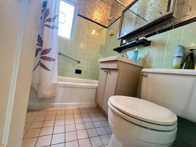 bathroom with tile patterned floors, toilet, tile walls, and shower / tub combo