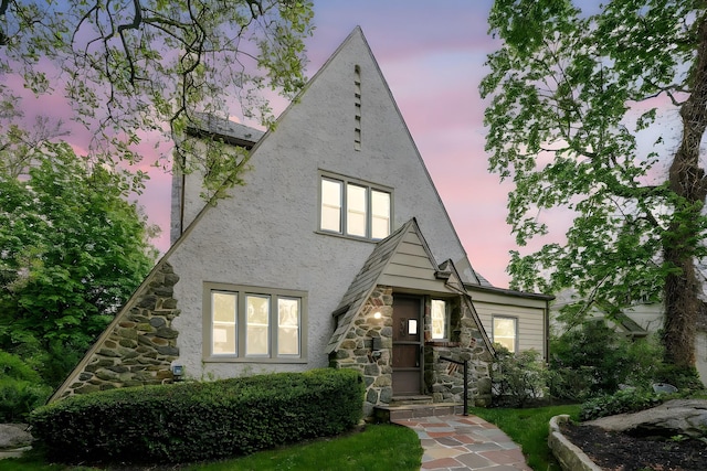 a-frame style home featuring stone siding and stucco siding
