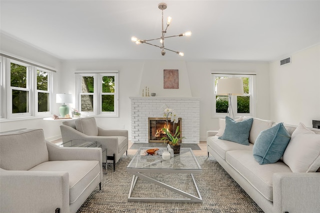 living room with a brick fireplace, an inviting chandelier, visible vents, and wood finished floors