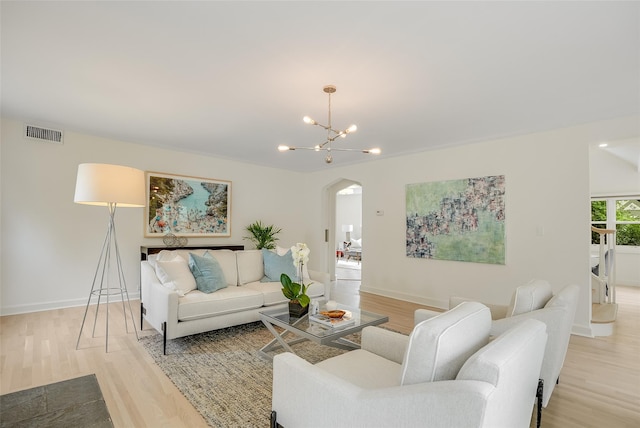 living room with light wood-style flooring, visible vents, baseboards, arched walkways, and a chandelier