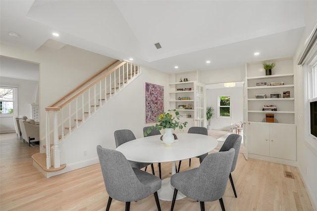 dining area featuring a healthy amount of sunlight, stairs, light wood-type flooring, and visible vents