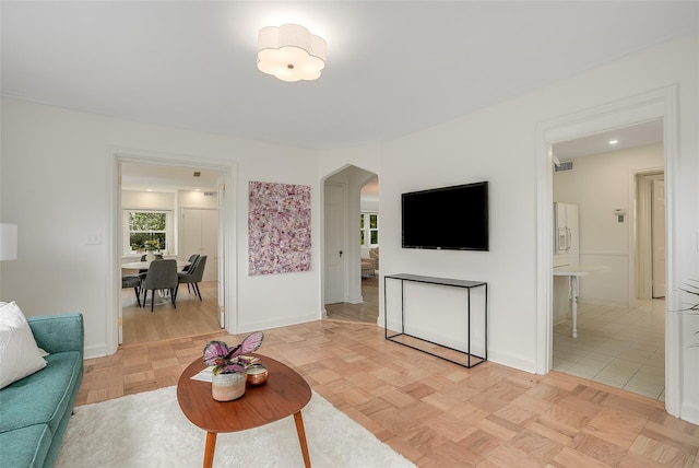 living room with arched walkways, baseboards, and visible vents