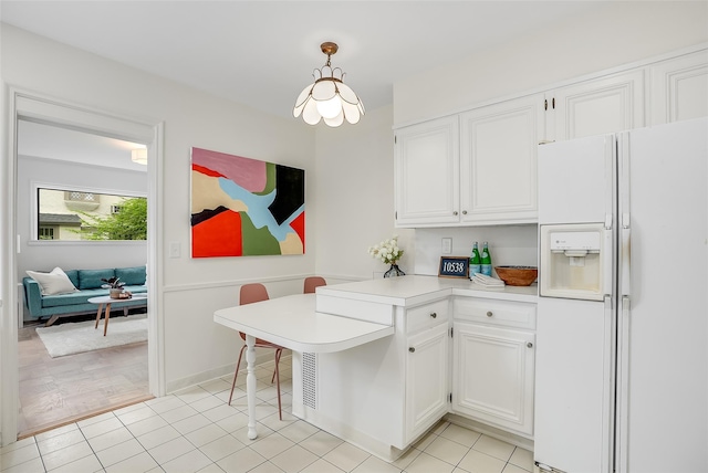 kitchen featuring white cabinets, light countertops, a peninsula, and white fridge with ice dispenser