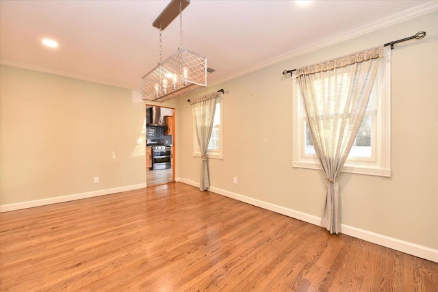 unfurnished room with hardwood / wood-style floors, an inviting chandelier, ornamental molding, and a healthy amount of sunlight