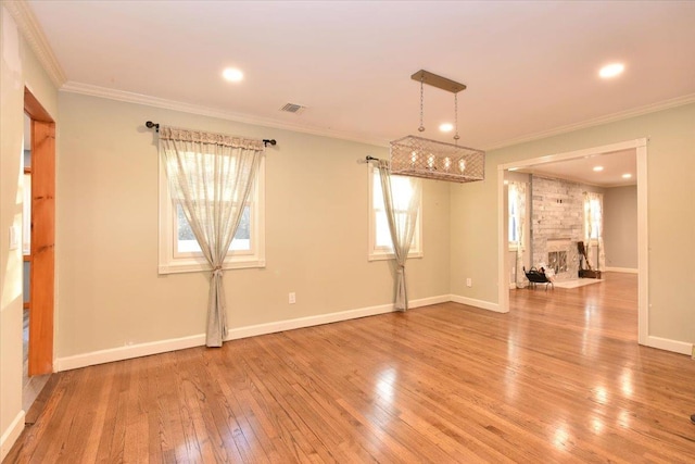 unfurnished room featuring hardwood / wood-style floors, a stone fireplace, and ornamental molding