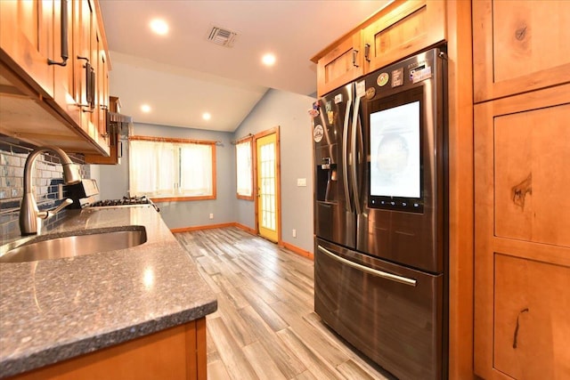 kitchen with sink, tasteful backsplash, stainless steel refrigerator with ice dispenser, lofted ceiling, and light wood-type flooring