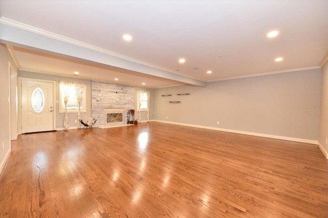 unfurnished living room featuring plenty of natural light, light hardwood / wood-style floors, crown molding, and a fireplace