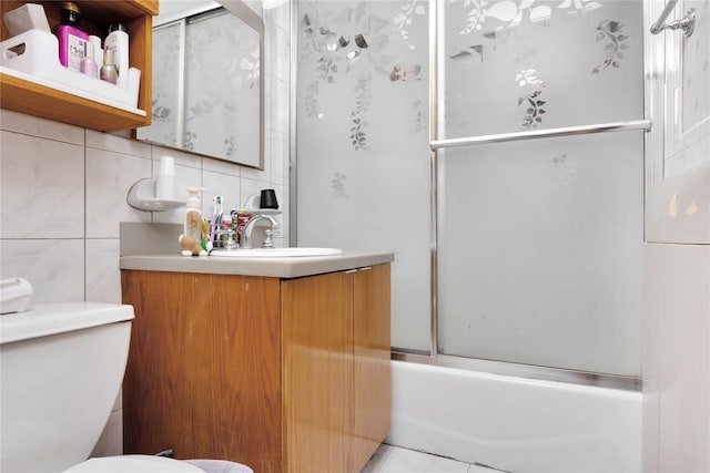 full bathroom featuring vanity, shower / bath combination with glass door, backsplash, toilet, and tile walls