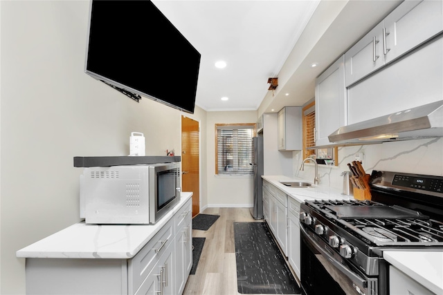 kitchen featuring sink, appliances with stainless steel finishes, light wood-type flooring, white cabinets, and ornamental molding