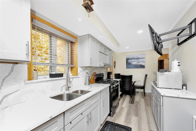 kitchen with gas stove, sink, tasteful backsplash, crown molding, and light wood-type flooring