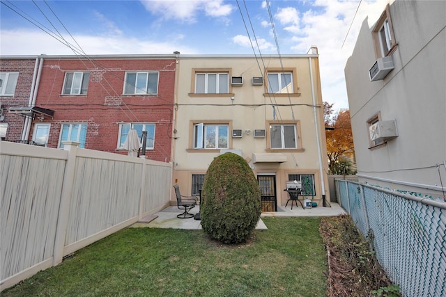 rear view of property featuring an AC wall unit, a patio area, and a lawn