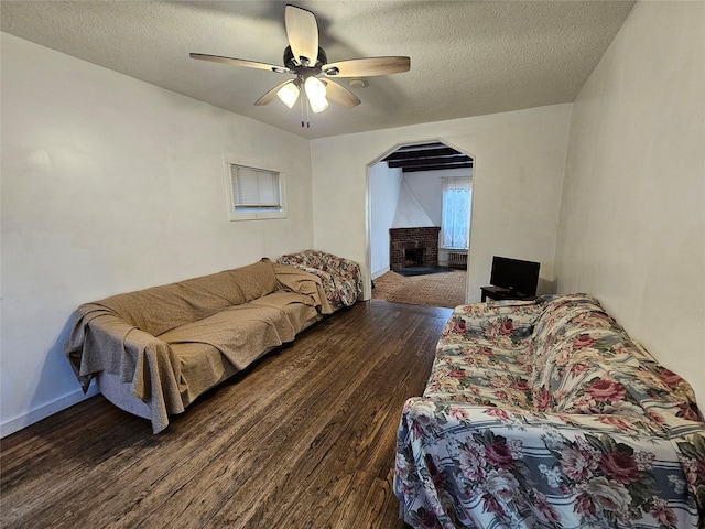 living room featuring ceiling fan, dark hardwood / wood-style flooring, and a textured ceiling