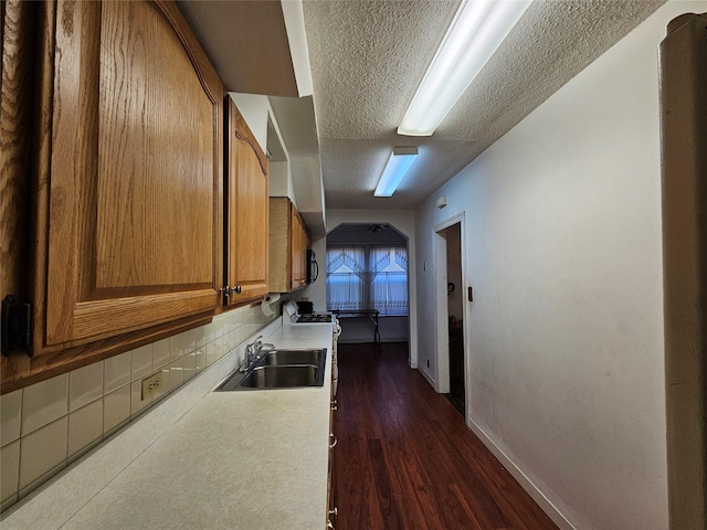 hallway featuring a textured ceiling, dark wood-type flooring, and sink