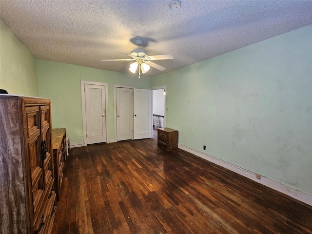 unfurnished bedroom featuring ceiling fan, dark hardwood / wood-style flooring, and a textured ceiling