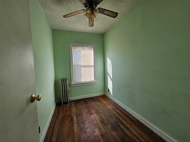 empty room featuring radiator, ceiling fan, dark wood-type flooring, and a textured ceiling