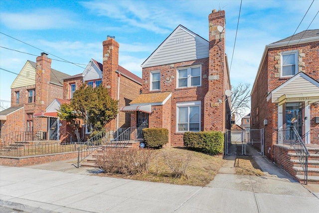 view of front of home with driveway, brick siding, fence, and a gate