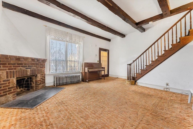 unfurnished living room featuring carpet floors, beam ceiling, radiator heating unit, a brick fireplace, and stairs