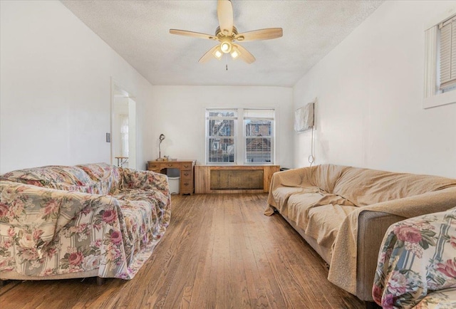 living room featuring a textured ceiling, wood finished floors, and a ceiling fan