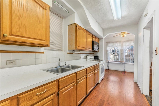 kitchen featuring light countertops, white range with gas cooktop, a sink, wood finished floors, and black microwave