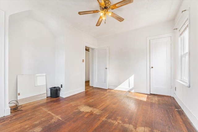 unfurnished bedroom with ceiling fan, a textured ceiling, baseboards, and wood finished floors