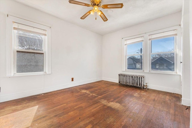 empty room featuring ceiling fan, a textured ceiling, dark wood-type flooring, baseboards, and radiator