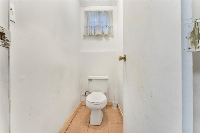 bathroom with tile patterned flooring, baseboards, and toilet