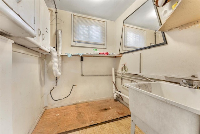 laundry area with light floors, a sink, and baseboards