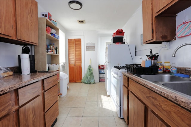 kitchen with light tile patterned floors, white gas range, and sink