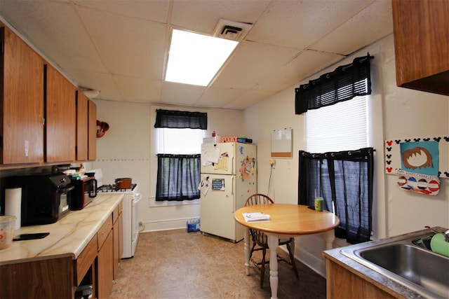 kitchen with white appliances, a paneled ceiling, and sink